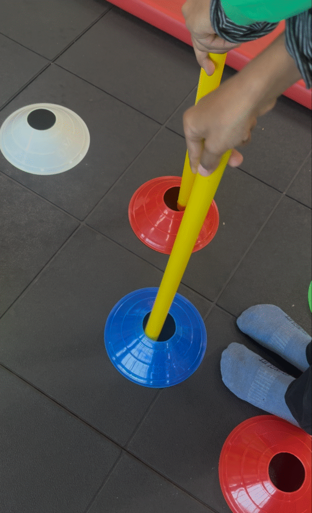 Child engaging in a fine motor skill activity using cones and rods as part of sensory integration therapy at Jewel Autism Center, Dubai.